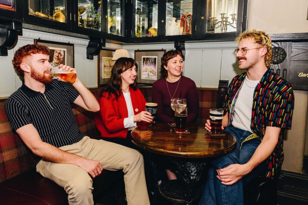 A group of people sat round a table drinking beer