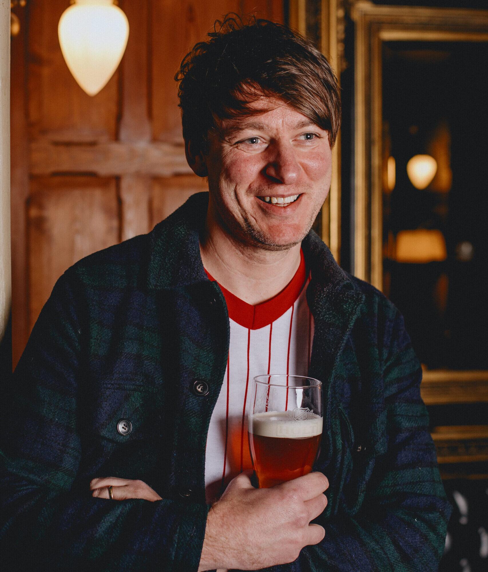 A man smiling holding a pint.