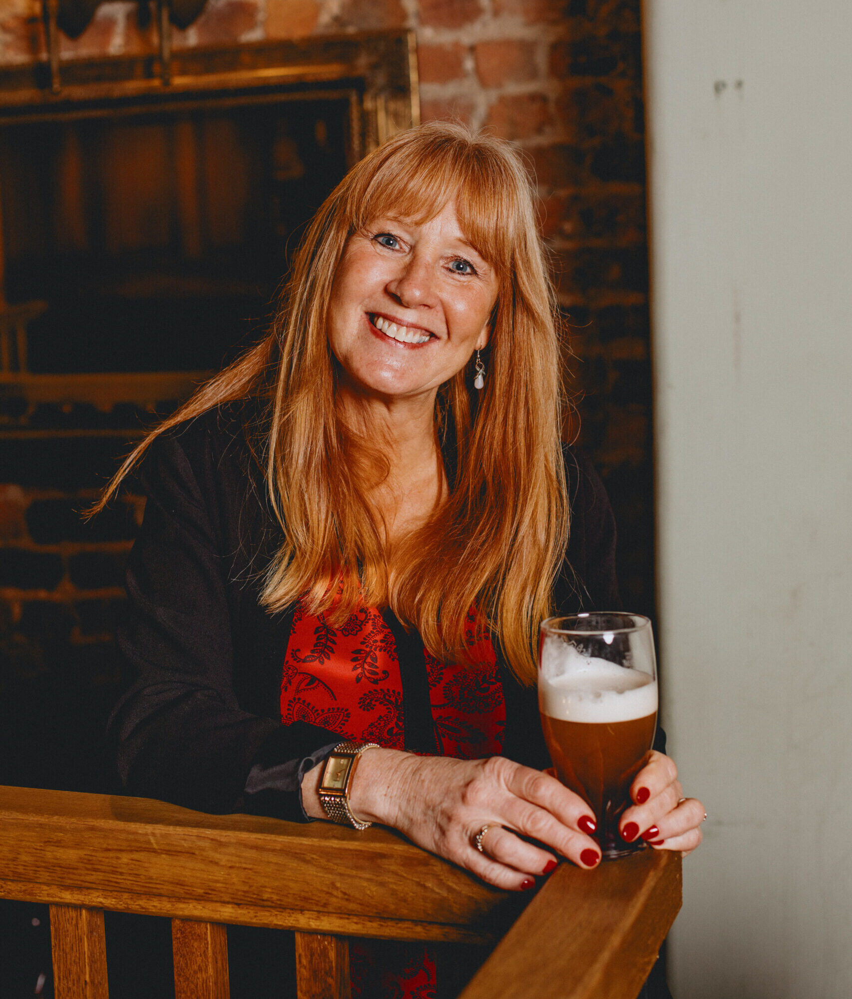 A woman smiling holding a pint of Bitter.