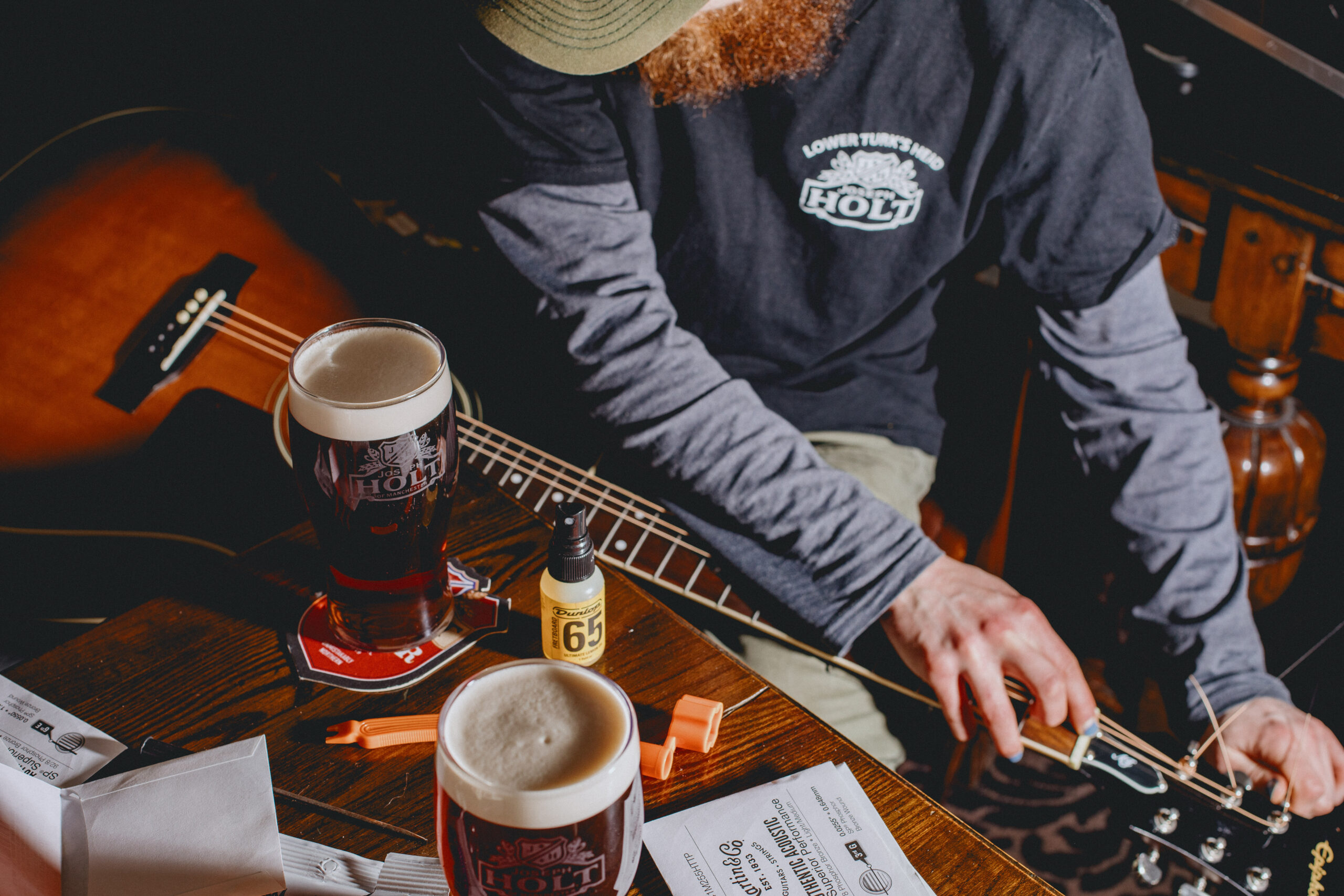 A pint of bitter with a man tuning a guitar.