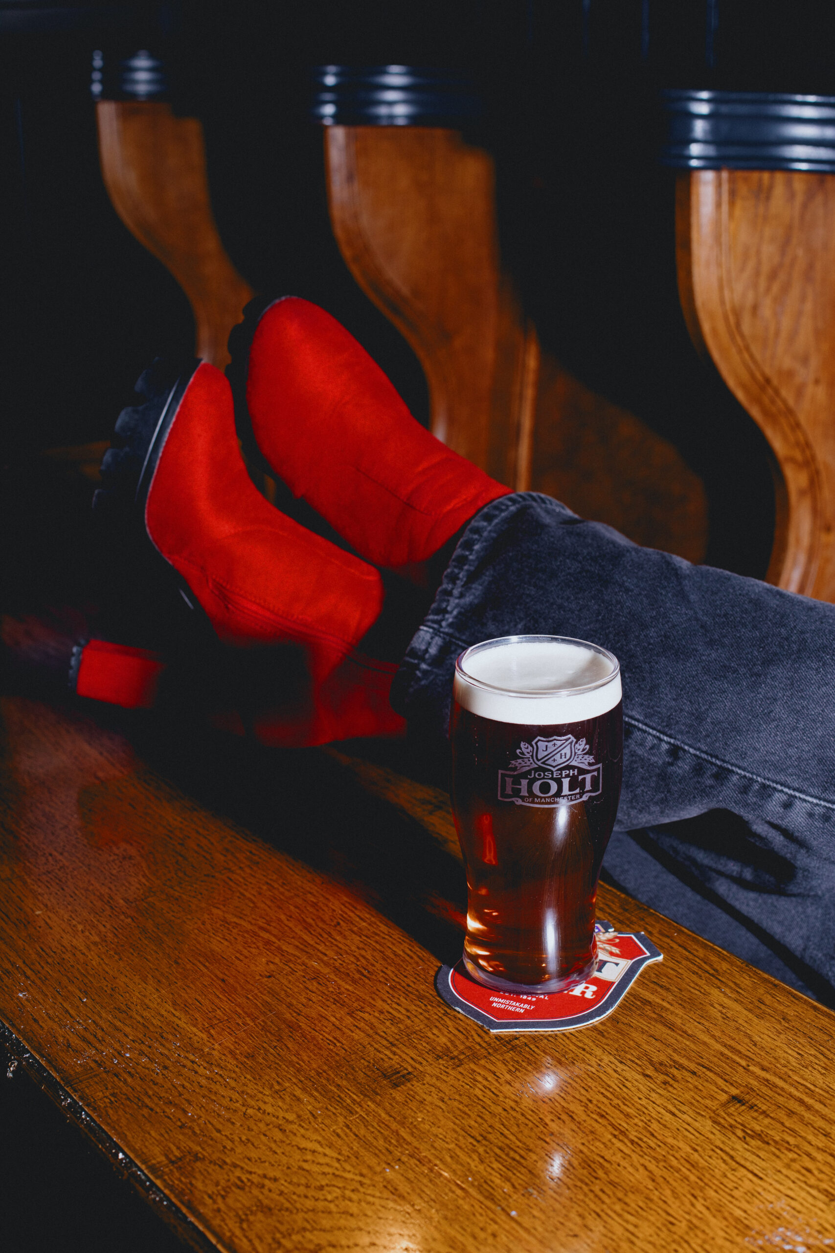 A pint of Bitter on a table with red boots.