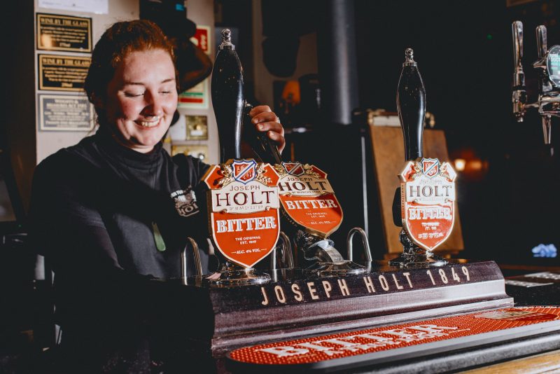 A woman pulling a pint of Bitter.