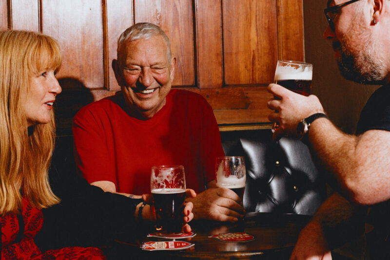 Two men and a woman sat round a table drinking Bitter talking.