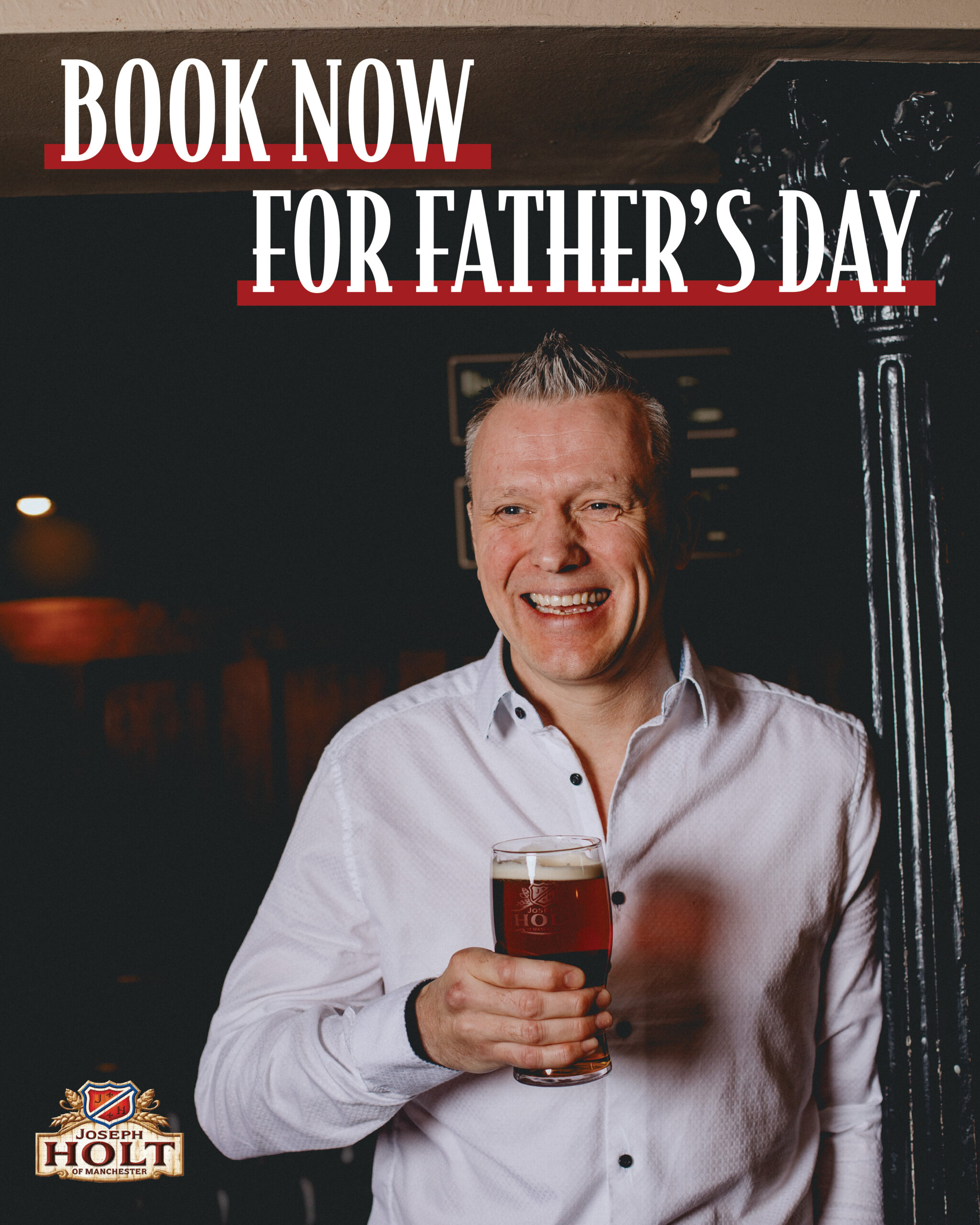 A man standing and smiling holding a beer.